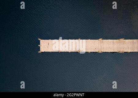 Vista ad occhio di uccelli del molo di legno che conduce al lago preso con il drone. Foto Stock