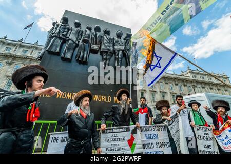 Londra, Regno Unito. 12 giugno 2021. Gli ebrei ortodossi mostrano il loro sostegno e bruciano una bandiera israeliana mentre cantano 'giù con Israele' - la protesta della Palestina fuori Downing Street a Whitehall ha programmato di sollevare la questione durante il vertice del G7. Il popolo si oppone agli ultimi piani di Israele di spostare i residenti palestinesi di Gerusalemme e il conseguente conflitto che si è verificato nella regione. La protesta è stata organizzata dalla Campagna di solidarietà della Palestina UK, CND, Stop the War e Friends of al Aqsa. Credit: Guy Bell/Alamy Live News Foto Stock