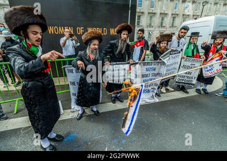 Londra, Regno Unito. 12 giugno 2021. Gli ebrei ortodossi mostrano il loro sostegno e bruciano una bandiera israeliana mentre cantano 'giù con Israele' - la protesta della Palestina fuori Downing Street a Whitehall ha programmato di sollevare la questione durante il vertice del G7. Il popolo si oppone agli ultimi piani di Israele di spostare i residenti palestinesi di Gerusalemme e il conseguente conflitto che si è verificato nella regione. La protesta è stata organizzata dalla Campagna di solidarietà della Palestina UK, CND, Stop the War e Friends of al Aqsa. Credit: Guy Bell/Alamy Live News Foto Stock