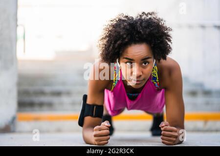 Donna afro atleta che fa pushup all'aperto. Foto Stock