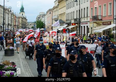 Varsavia, Varsavia, Polonia. 12 giugno 2021. I manifestanti marciano sventolando bandiere polacche durante una manifestazione contro i vaccini il 12 giugno 2021 a Varsavia, Polonia. Alcune migliaia di persone, soprattutto anti-vaxxers e covid-19 deniers hanno marciato attraverso la città per protestare contro i certificati digitali Covid-19 e vaccini contro covid-19. Credit: Aleksander Kalka/ZUMA Wire/Alamy Live News Foto Stock