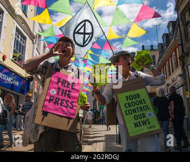 Falmouth, Cornovaglia, Regno Unito 12 giugno 2021 la ribellione per l’estinzione marciò in protesta contro le politiche di ‘lavaggio delle greenwashing’ del governo e degli affari al vertice del G7. I ribelli rossi guidano la marcia attraverso il centro città unendosi ai medici di XR e scrubber sporchi, terminando al centro di media. Foto Stock