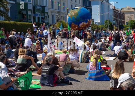 Falmouth, Cornovaglia, Regno Unito 12 giugno 2021 la ribellione per l’estinzione marciò in protesta contro le politiche di ‘lavaggio delle greenwashing’ del governo e degli affari al vertice del G7. I ribelli rossi guidano la marcia attraverso il centro città unendosi ai medici di XR e scrubber sporchi, terminando al centro di media. Foto Stock