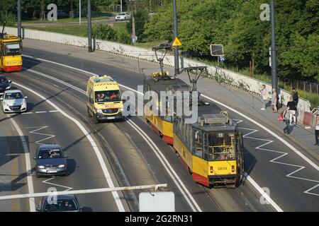 Varsavia, Polonia - 11 giugno 2021: Ambulanza gialla con luci lampeggianti in corsa sulla pista del tram per aggirare l'ingorgo nei pressi della città vecchia di Varsavia. Foto Stock