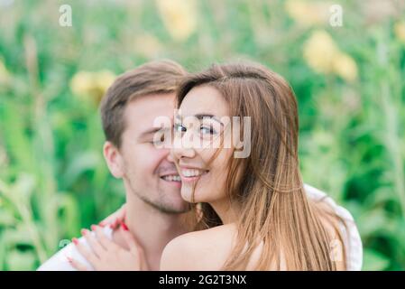 Bella donna splendida ed elegante bel maschio, coppia rustica in un campo di girasole baciare Foto Stock