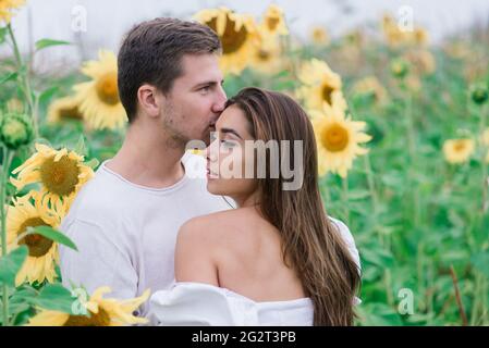 Bella donna splendida ed elegante bel maschio, coppia rustica in un campo di girasole baciare Foto Stock