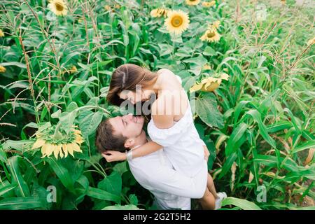 Bella donna splendida ed elegante bel maschio, coppia rustica in un campo di girasole baciare Foto Stock