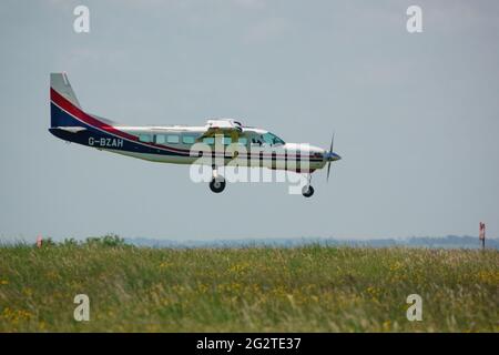 Una grande carovana cessna 208B torna a terra su una pista di erba dopo aver abbandonato il team di visualizzazione del paracadute Red Devils Foto Stock