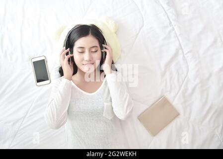 Piacere allegro wellness woman concetto. Felice adolescente donna che ascolta la musica indossa le cuffie da smartphone all'aperto nel parco. Musica mentale Foto Stock