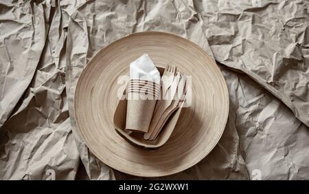 Tazze monouso, forcelle, coltelli su sfondo cartaceo. Foto Stock