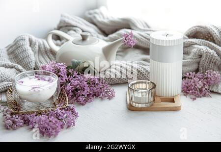 Delicato arrangiamento primaverile con fiori in vaso, un bicchiere di latte e dettagli di arredamento per la casa. Foto Stock