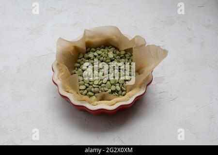 Pasta per tartine da forno cieca con lenticchie verdi in una forma di torta rossa mini Foto Stock