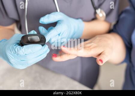 Il personale infermieristico utilizza un pulsossimetro per misurare la saturazione di ossigeno nel sangue del paziente anziano Foto Stock