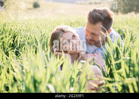 Bella giovane donna flirta con il suo uomo mentre si siede in erba, stile di vita ritratto Foto Stock