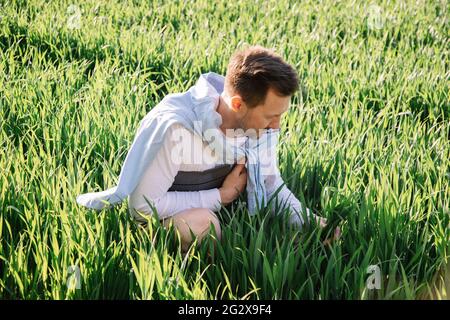 Giovane agricoltore con piegatrice sotto il braccio seduto in campo 40 anni di controllo del suo raccolto di foraggio, piccola bussiness idea foto Foto Stock