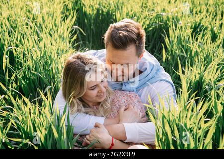 Giovane coppia si è ritirata in natura e ha un grande tempo seduto in erba verde in natura, Amore Foto Stock