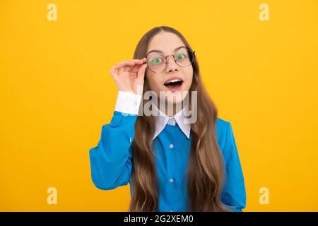 Curioso scuola età ragazza bambino sguardo attraverso occhiali sfondo giallo, curiosità Foto Stock