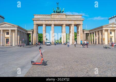 Moderno scooter elettrico di fronte alla porta di Brandeburgo (Brandenburger Tor) nel centro storico e commerciale di Berlino, in Germania, al sole d'estate Foto Stock