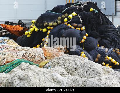 Un mucchio di reti da pesca commerciali disparate realizzate con vari materiali, alcune con galleggianti attaccati. Foto Stock