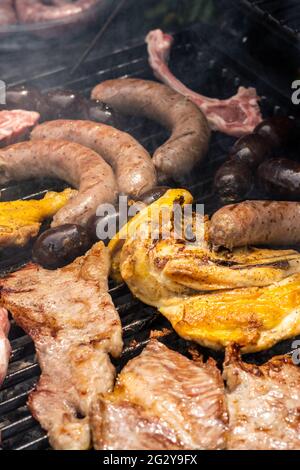 Vari tipi di carne, pollo, salsicce, salsiccia di sangue, agnello su una griglia di cron in giardino Foto Stock