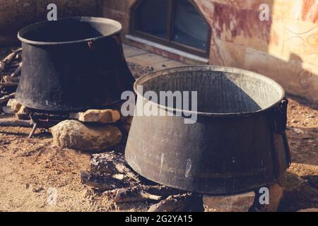 Cucinare in due vecchi cavoldri di soia sul fuoco in giornata di sole. Vista ravvicinata. Immagine con tonalità retrospettiva. Foto Stock