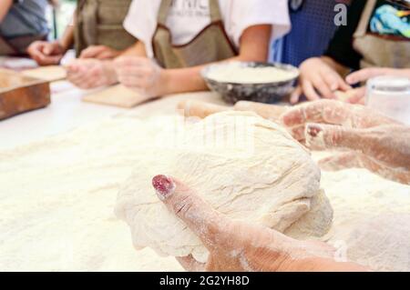 Chef donna che tiene l'impasto. Il cuoco insegna ai bambini a fare l'impasto. Master class in cottura. Cucina a casa. v Foto Stock