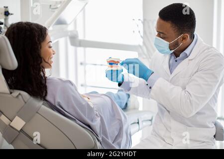 Igiene dentale. Dentista che tiene modello della ganascia e che mostra come spazzolare i denti Foto Stock