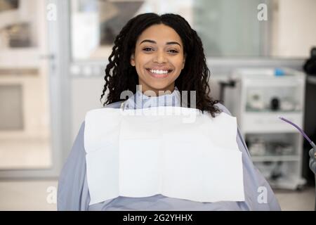 Ritratto di Felice paziente femmina nero seduto in sedia in Dental Clinic Foto Stock