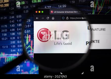 LG Electronics logo aziendale su un sito web con sviluppi del mercato azionario sfocato in background, visto su uno schermo del computer attraverso una lente di ingrandimento Foto Stock