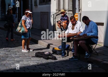 Tallinn, Estonia -- 23 luglio 2019. Una foto di busker che suonano strumenti tradizionali a Tallinn, Estonia, mentre i turisti guardano sopra. Foto Stock