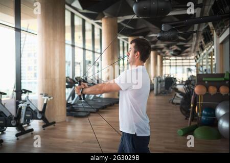 Uomo che si esercita in palestra su una macchina pec deck per l'allenamento crossover del cavo del petto e dei muscoli pettorali Foto Stock