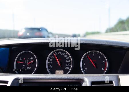 Primo piano del cruscotto di un'auto. Vista sfocata della strada con le vetture in movimento attraverso il parabrezza. Foto Stock