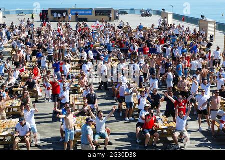 Hastings, East Sussex, Regno Unito. 13 giugno 2021. Gli amanti dell'Inghilterra bevono all'aperto nelle giornate di sole nella zona dei tifosi del molo di Hastings, che ha fornito un grande schermo e un bar con birra. L'Inghilterra vince 1-0 Photo Credit: Paul Lawrenson /Alamy Live News Foto Stock