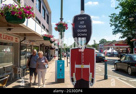 Ascot, Berkshire, Regno Unito. 13 giugno 2021. La gente cammina oltre non lasciare la vostra guardia giù le indicazioni in Ascot High Street. Il numero di risultati positivi di Covid-19 nel Berkshire è in aumento su un tasso giornaliero come la variante indiana di Covid-19 sweep in tutto il Regno Unito. Boris Johnson dovrebbe annunciare domani che la revoca delle restrizioni di blocco di Covid-19 deve essere messa in attesa per un altro mese. Credito: Maureen McLean/Alamy Foto Stock