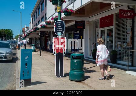 Ascot, Berkshire, Regno Unito. 13 giugno 2021. La gente cammina oltre non lasciare la vostra guardia giù le indicazioni in Ascot High Street. Il numero di risultati positivi di Covid-19 nel Berkshire è in aumento su un tasso giornaliero come la variante indiana di Covid-19 sweep in tutto il Regno Unito. Boris Johnson dovrebbe annunciare domani che la revoca delle restrizioni di blocco di Covid-19 deve essere messa in attesa per un altro mese. Credito: Maureen McLean/Alamy Foto Stock