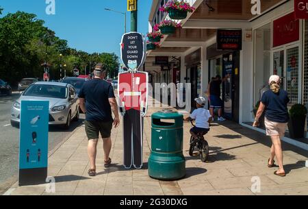 Ascot, Berkshire, Regno Unito. 13 giugno 2021. La gente cammina oltre non lasciare la vostra guardia giù le indicazioni in Ascot High Street. Il numero di risultati positivi di Covid-19 nel Berkshire è in aumento su un tasso giornaliero come la variante indiana di Covid-19 sweep in tutto il Regno Unito. Boris Johnson dovrebbe annunciare domani che la revoca delle restrizioni di blocco di Covid-19 deve essere messa in attesa per un altro mese. Credito: Maureen McLean/Alamy Foto Stock