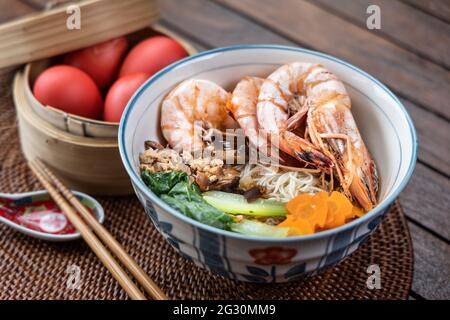 Primo piano su servire di noodle longevità di compleanno con uova rosse, una tradizione tra i cinesi durante le celebrazioni di compleanno Foto Stock
