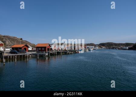 17 aprile 2021 - Hamburgsund, Svezia: Un pittoresco villaggio di pescatori sulla costa occidentale svedese. Tradizionali capanne di mare rosso e un cielo blu sullo sfondo Foto Stock