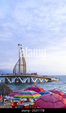 La scultura a vela e il molo cambiano colore di notte - inaugurato nel 2013 e progettato dall'architetto messicano Jesus Torres Vega, vista sui ombrelloni da spiaggia Foto Stock