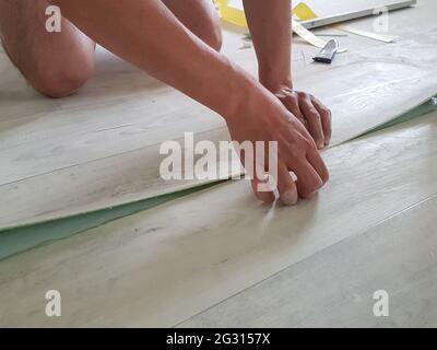 Installazione del linoleum. Il lavoratore colla le parti di linoleum Foto Stock