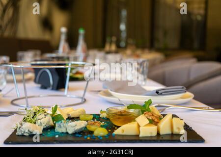 Spuntini assortiti su un piatto di pietra nera su un tavolo del ristorante su uno sfondo della finestra Foto Stock