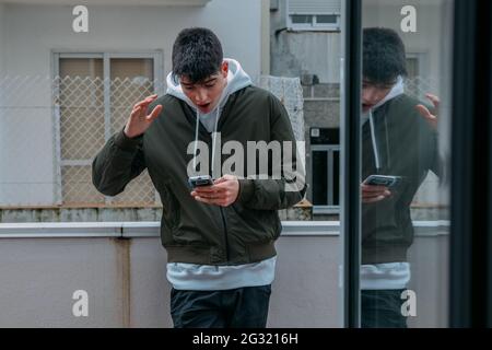 ragazzo adolescente guardando il telefono cellulare stupito Foto Stock