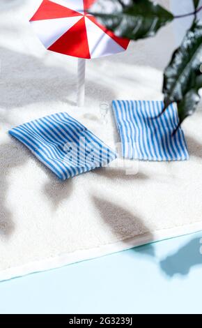 Spiaggia estiva, lettini, ombrellone, rami di alberi, ombre. Concetto di minimalismo. Relax e tranquillità. Foto Stock