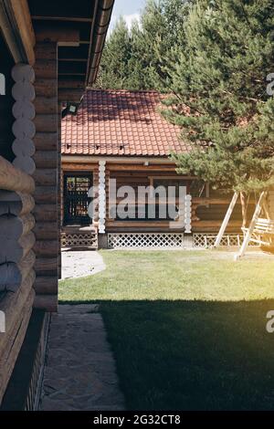 La facciata della moderna casa in legno fatta di tronchi rotondi. Soggiorno confortevole, riposo fuori città e relax nella natura. Costruzione suburbana da na Foto Stock