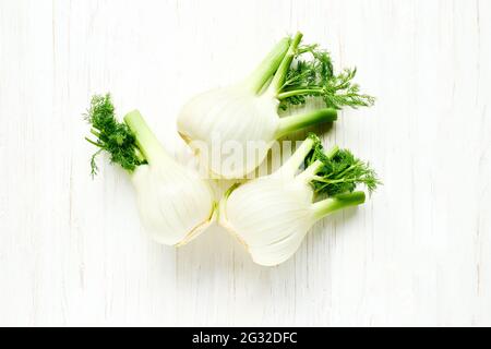 Bulbi freschi di finocchio fiorentino su sfondo bianco di legno. Vista dall'alto con verdure primaverili organiche grezze. Alimentazione sana e genuina Foto Stock