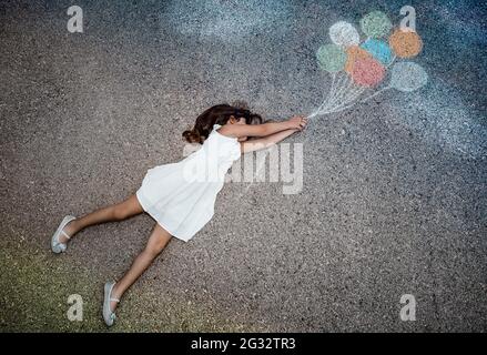 Immagine concettuale della libertà gioia e felicità. Little Girl volare via su palloncini colorati. Godendo la vita. L'Infanzia sognante. Immaginazione creativa. Foto Stock