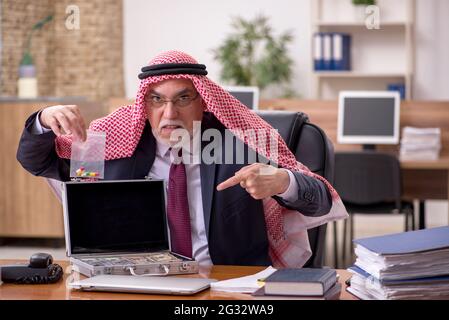 Dipendente arabo anziano che vende narcotici sul posto di lavoro Foto Stock