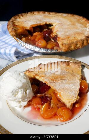 Una fetta di torta di ciliegie rimossa da una torta di ciliegie fresca fatta in casa con Rainer e ciliegie rosse scure servite con gelato alla vaniglia Foto Stock