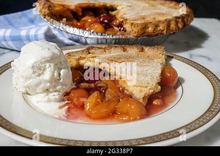 Una fetta di torta di ciliegie rimossa da una torta di ciliegie fresca fatta in casa con Rainer e ciliegie rosse scure servite con gelato alla vaniglia Foto Stock