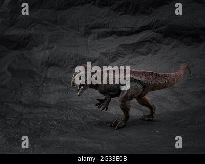 modello singolo platico di dinosauro giocattolo su sfondo scuro Foto Stock